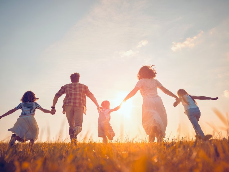 famiglia mano nella mano corre in un prato