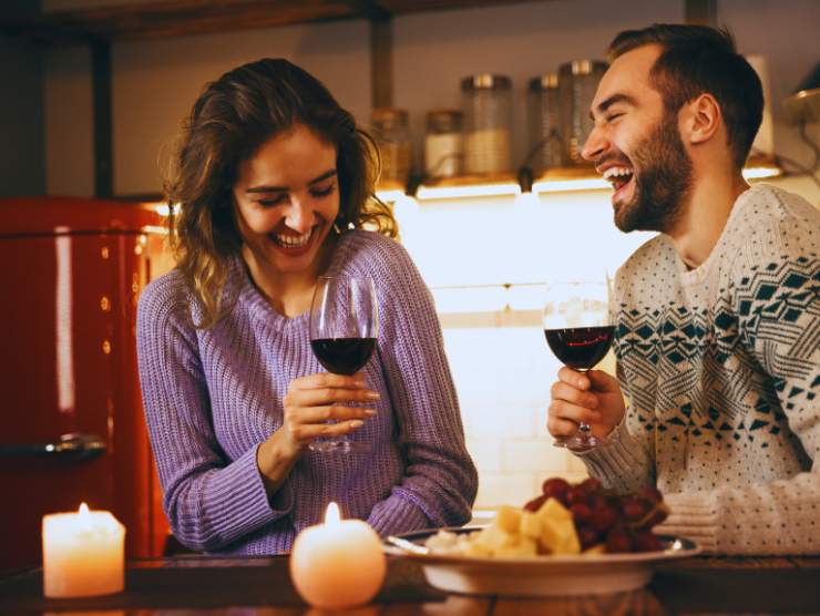 coppia conviventi brinda con vino in mano in casa