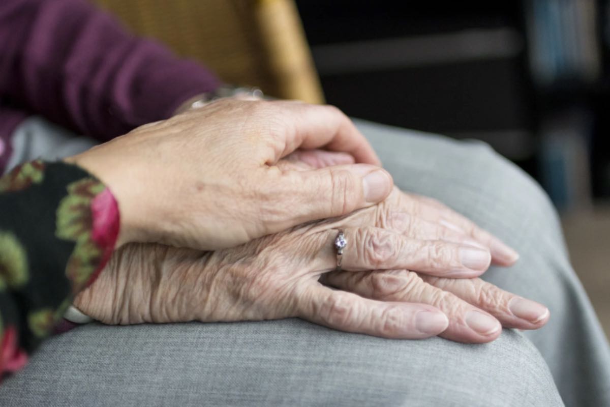 Mano conforta le mani di una signora anziana