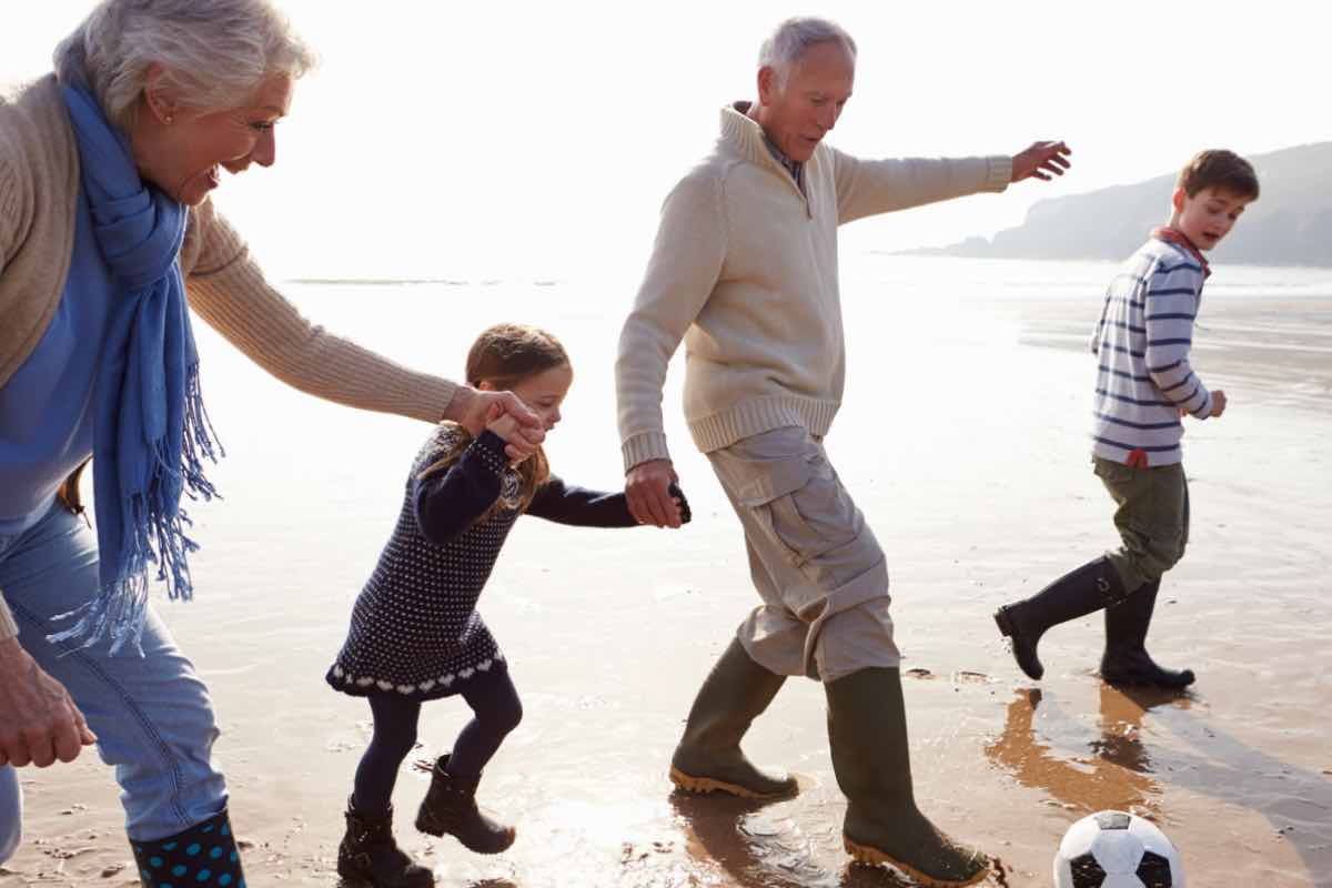 nonni che giocano a calcio con i nipoti sulla spiaggia