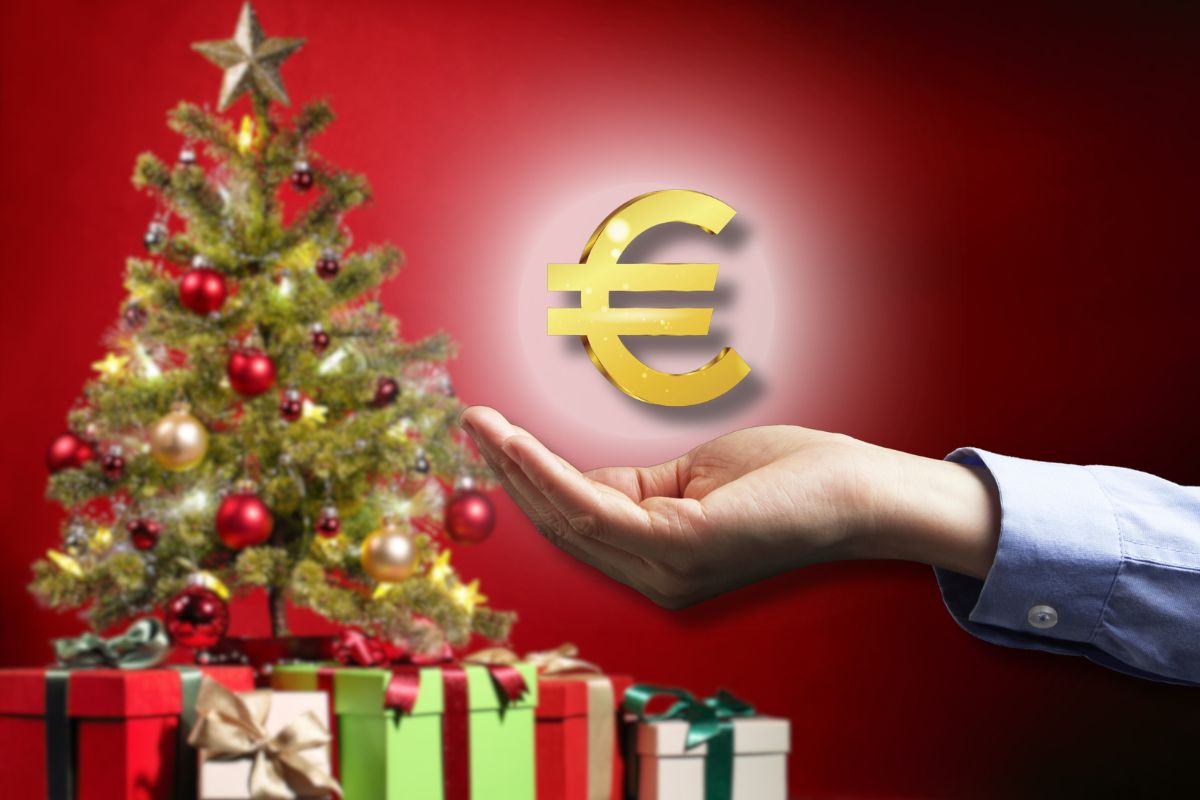 simbolo euro in mano e albero e regali di Natale