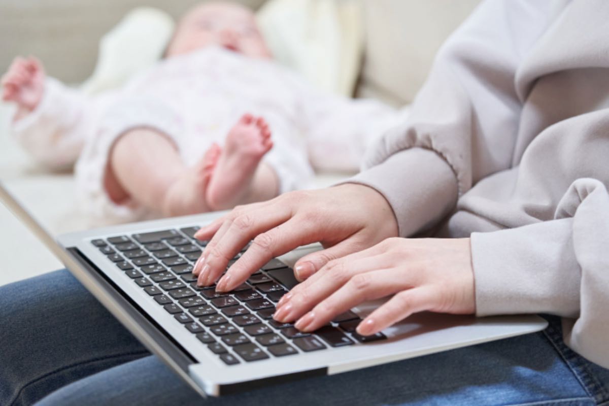 Mamma al computer con neonato vicino