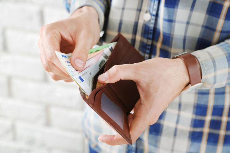 uomo con in mano portafoglio con banconote euro