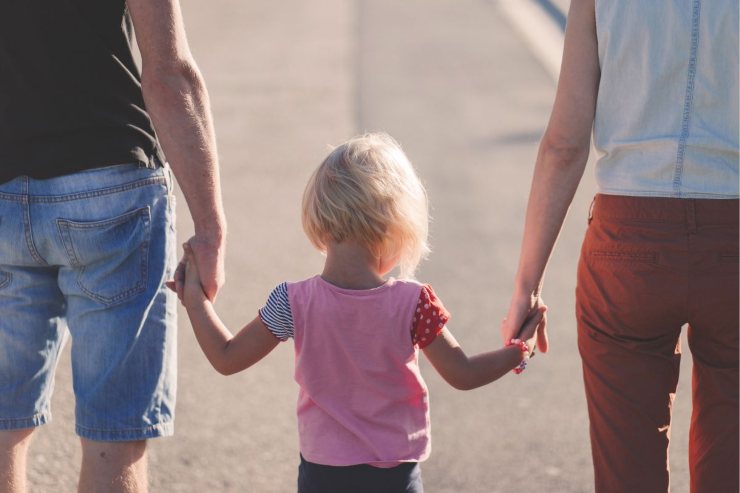 bambina mano nella mano con i genitori