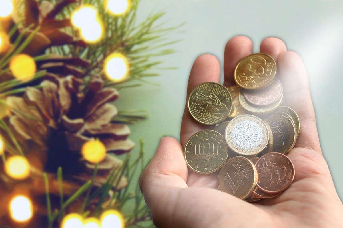 albero di natale su sfondo e focus su mano con monete euro bonus con gesto da restituire