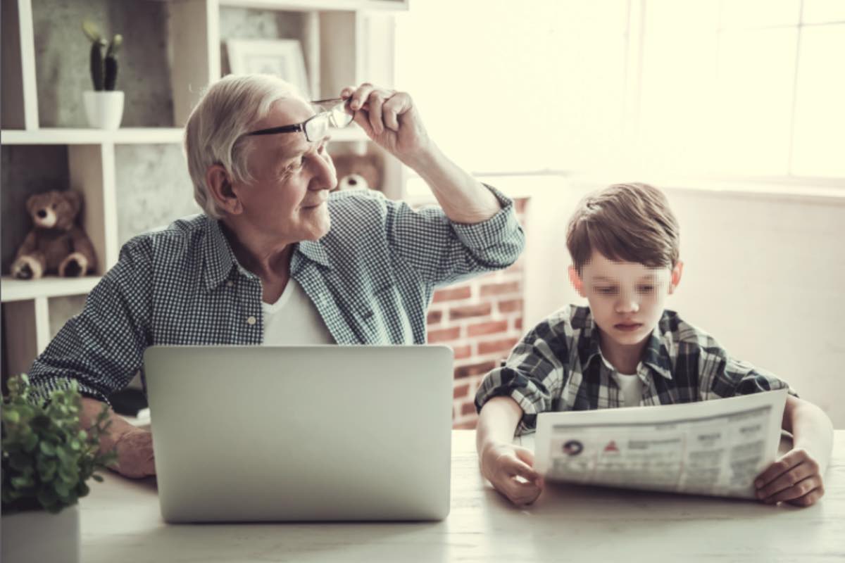 Nonno al computer con nipote vicino