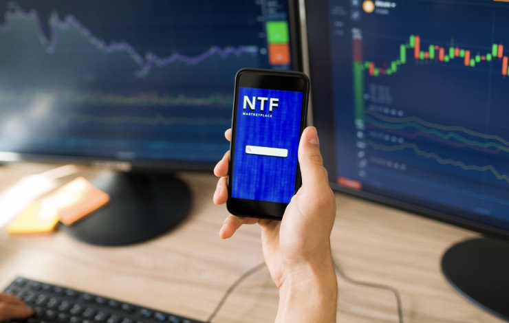 Smartphone con app NTF e grafici degli indici di mercato sullo sfondo 