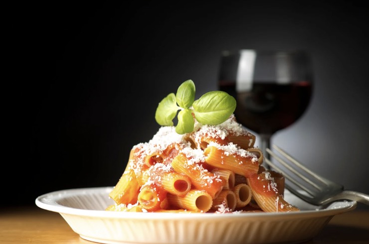 piatto di pasta al sugo con basilico e bicchiere di vino: simbolo di italianità