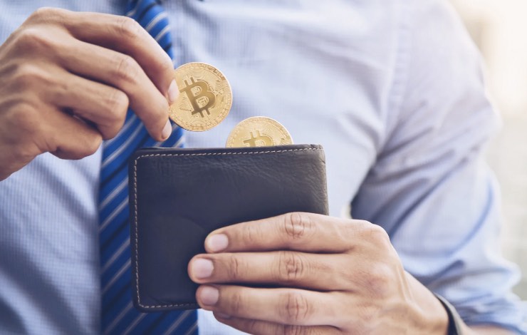 uomo che conta i bitcoin nel portafoglio 