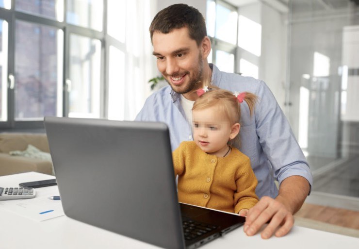 Papà al lavoro sul computer con in braccio il figlio