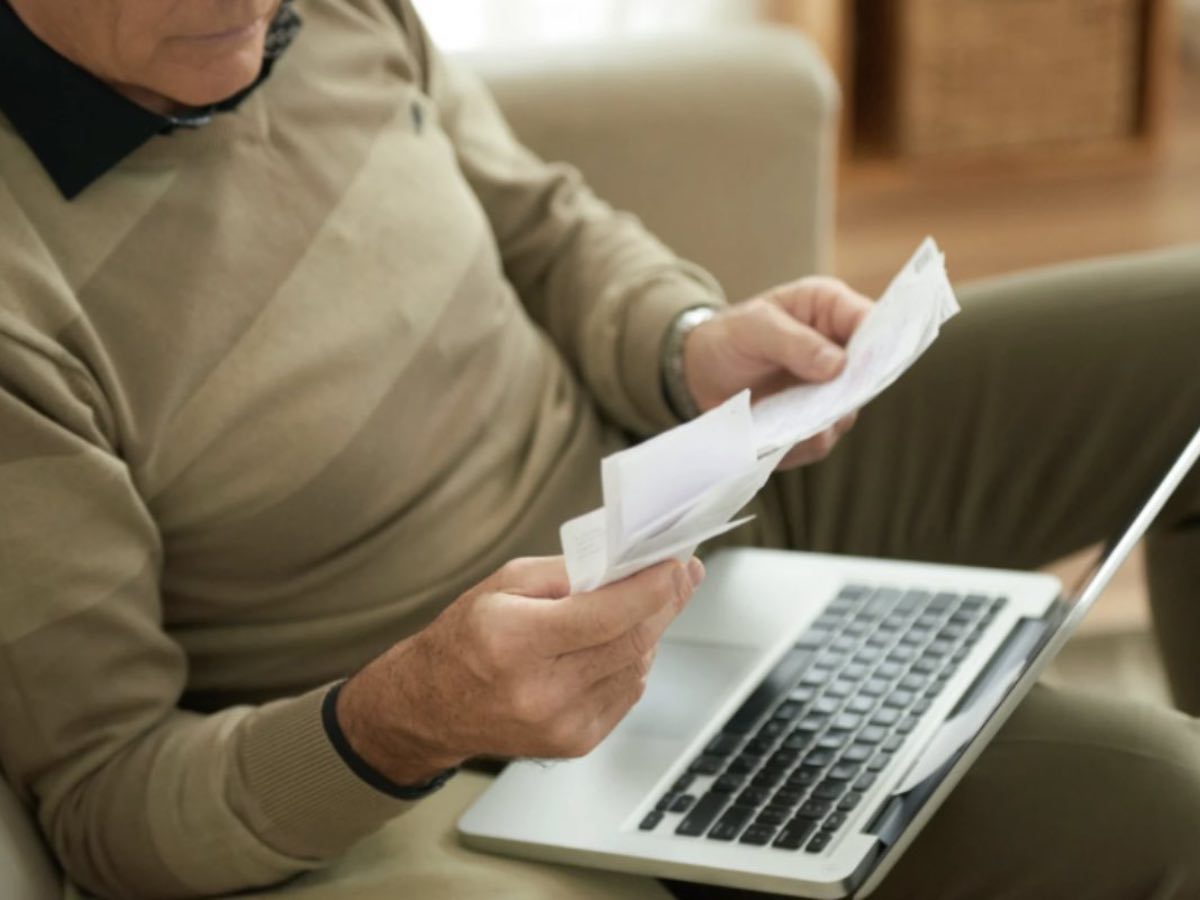 Anziano che controlla le bollette davanti al computer