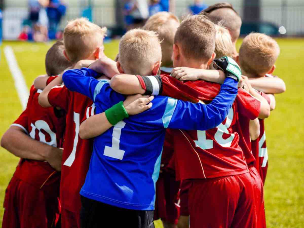 Squadra di calcio di bambini che si abbracciano nel campo