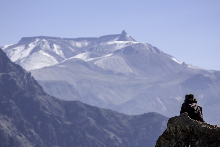 uomo che da seduto scruta le montagne intorno a lui