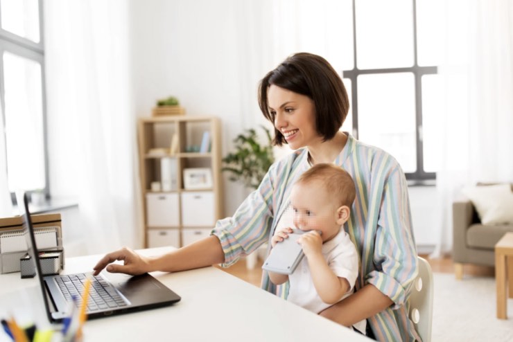 Mamma lavora al computer con il bambino in braccio