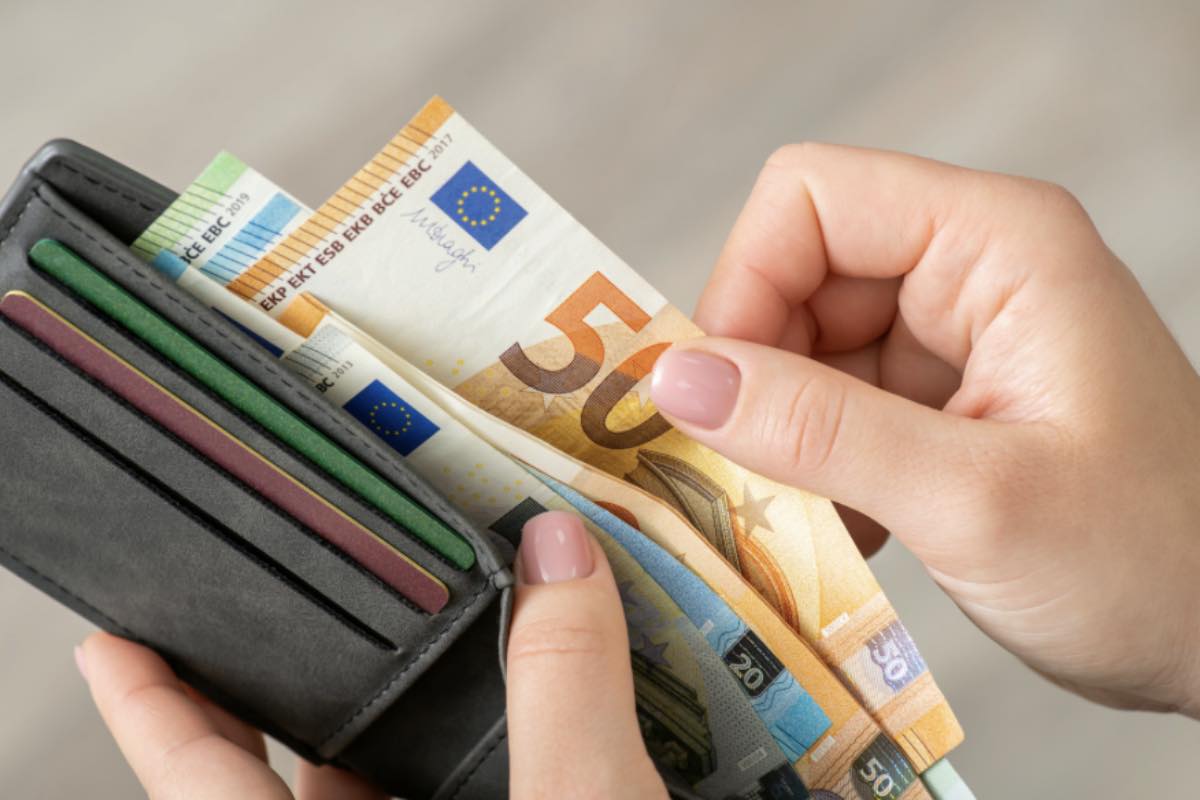 Mano che estrae banconota in euro dal portafoglio