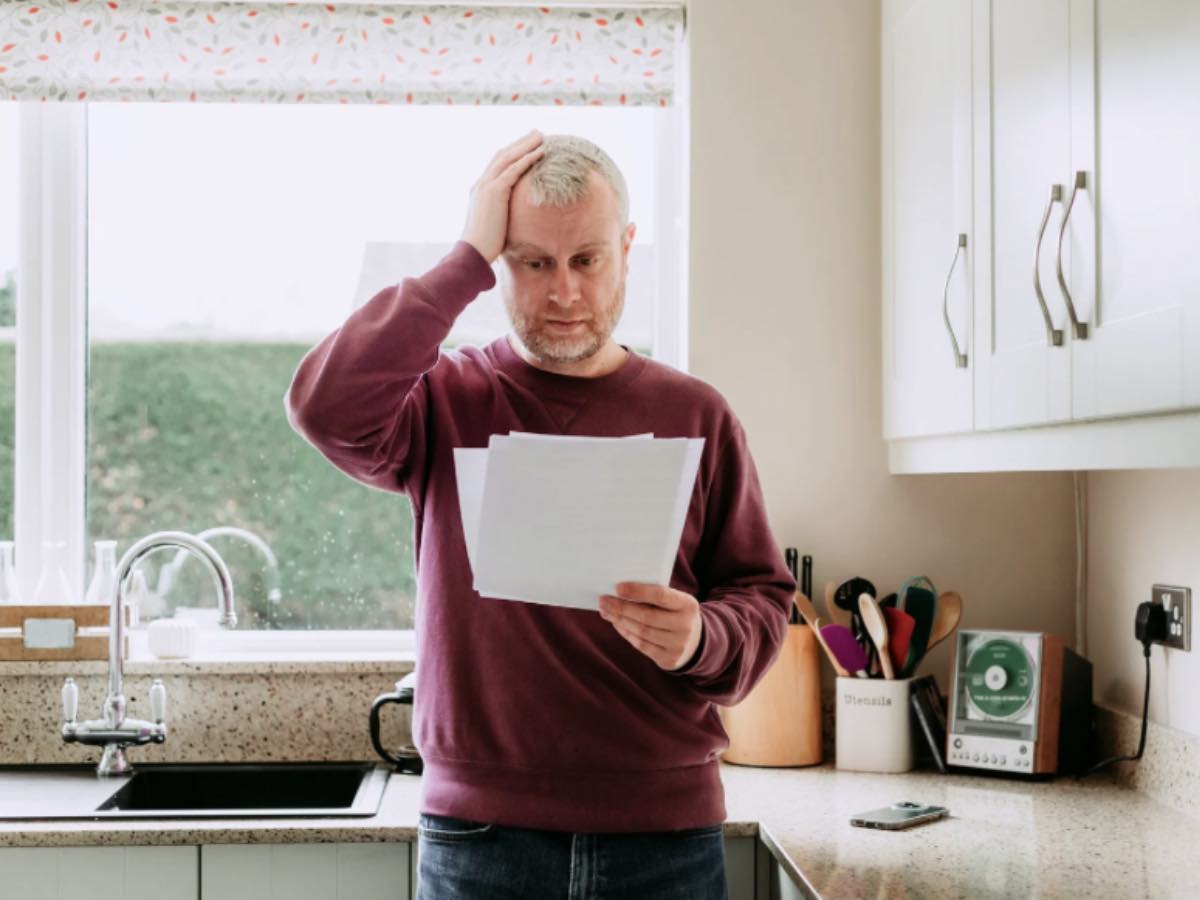 Uomo con documenti in mano, mani nei capelli