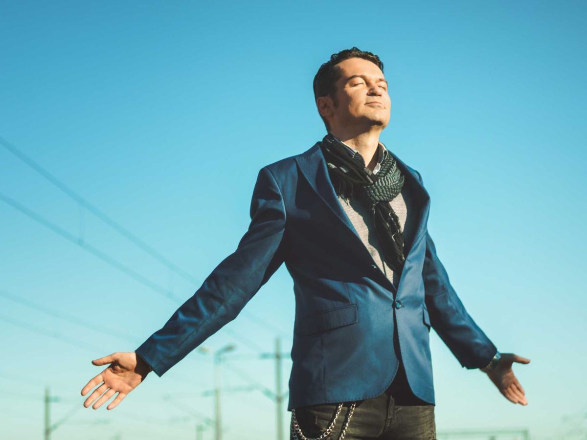 Uomo vestito elegante che respira con le braccia aperte, sensazione di libertà