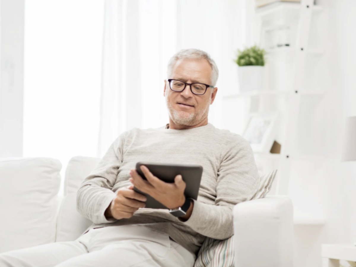 Uomo di mezza età sul divano consulta il tablet