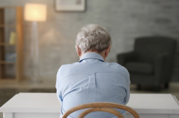 Signora anziana triste, siede a un tavolo in casa