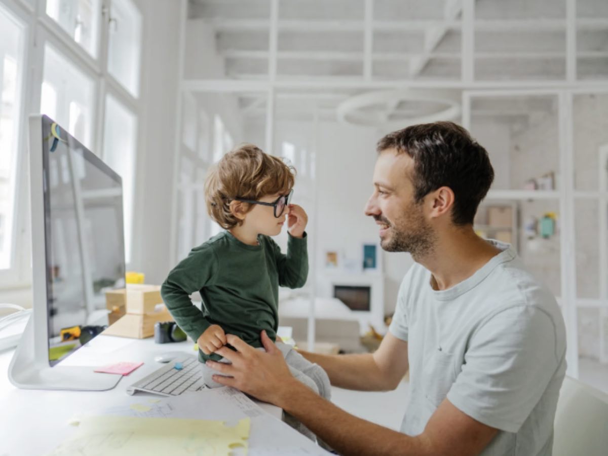 Papà al lavoro in ufficio con il figlio sulla scrivania