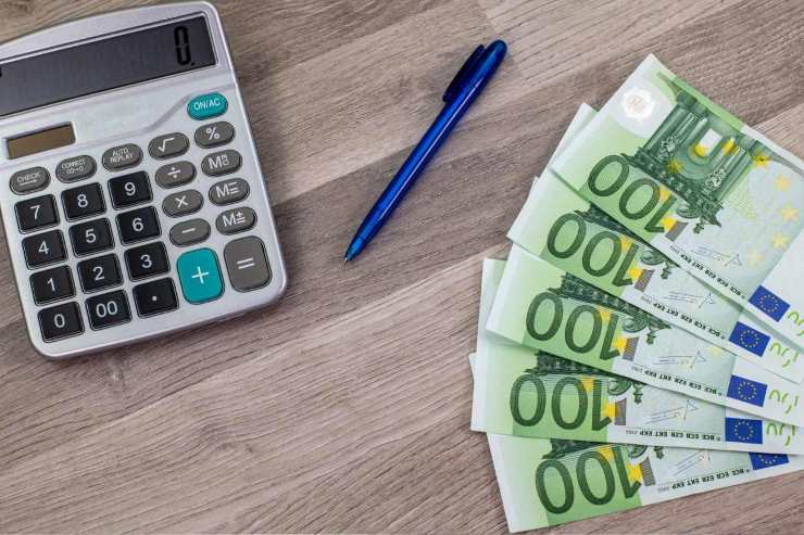 Tavolo con calcolatrice, biro e cinque banconote da 100 euro