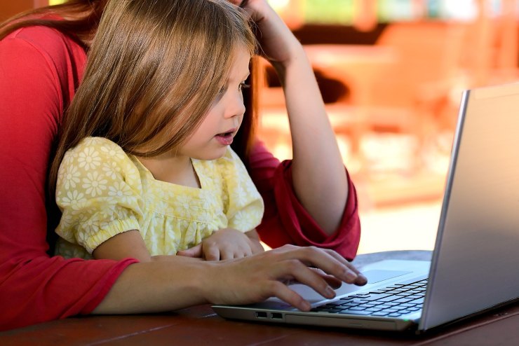 bambina seduta davanti al pc in braccio alla mamma